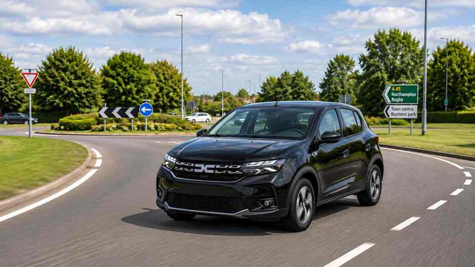 Black Dacia Sandero exiting a roundabout