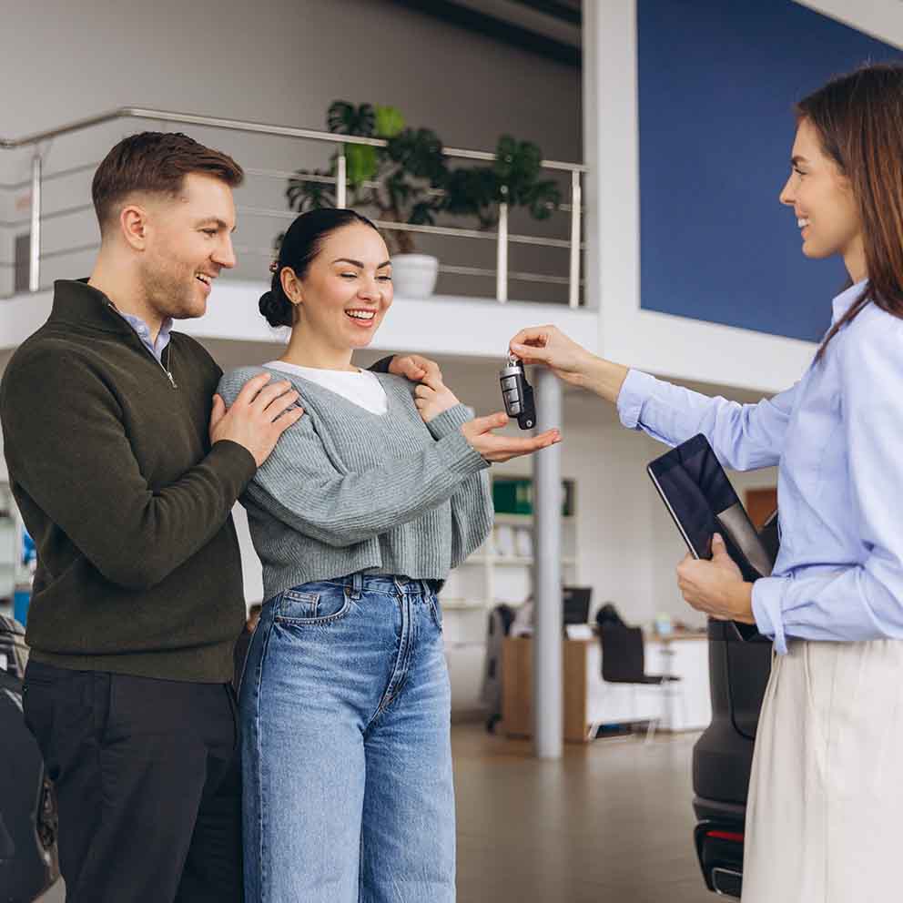 car agent handing couple keys by car