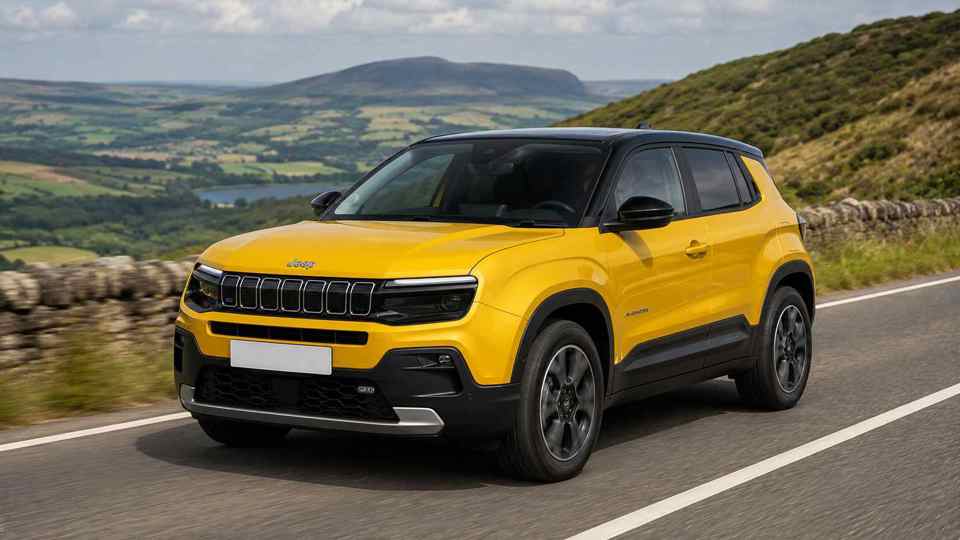 Yellow Jeep Avenger driving on a hill with a lake in the background